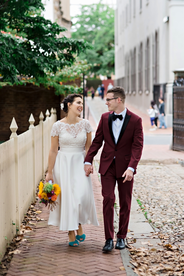 A wedding couple walking along the cobblestone streets and laughing .